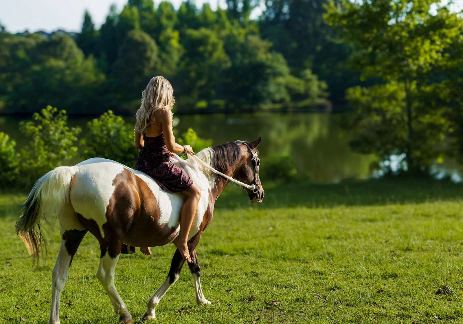 Aubree riding her horse Wrangler through an open Georgia pasture beside the lake